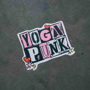 A sticker with the text 'YOGA PUNK' in bold letters, surrounded by heart shapes and star graphics, on a gray background.