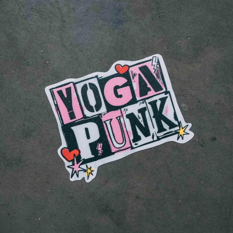 A sticker with the text 'YOGA PUNK' in bold letters, surrounded by heart shapes and star graphics, on a gray background.